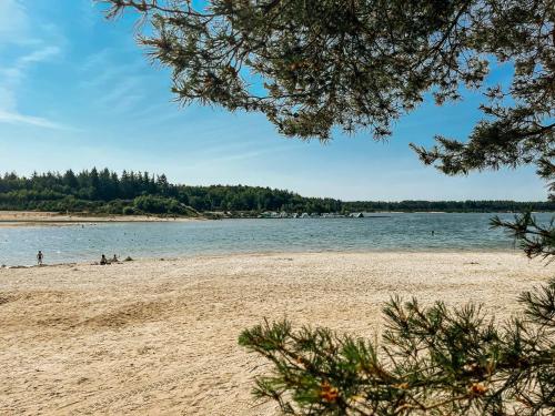 a beach with people sitting on the sand and water at De Strandhoed Drenthe - Bos & Meer in Gasselte