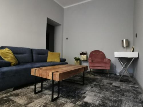a living room with a blue couch and a wooden coffee table at Noclegi Gwardia in Koszalin