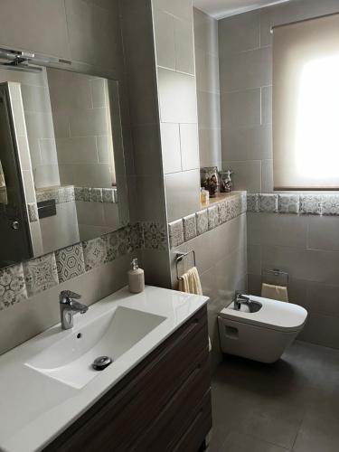 a bathroom with a sink and a toilet and a mirror at La terraza de la subbética in Luque