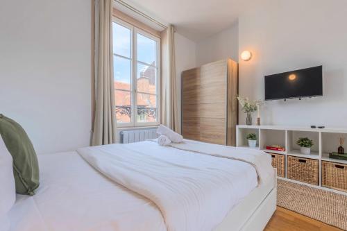 a white bedroom with a large bed and a window at Grand Place very well located studio in Lille