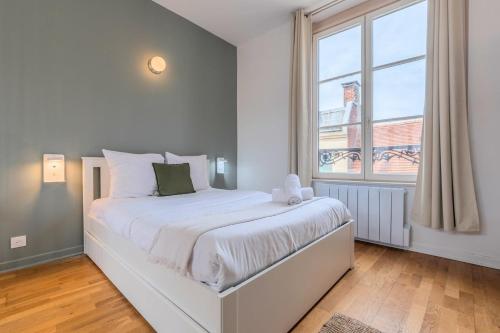 a white bedroom with a large bed and a window at Grand Place very well located studio in Lille