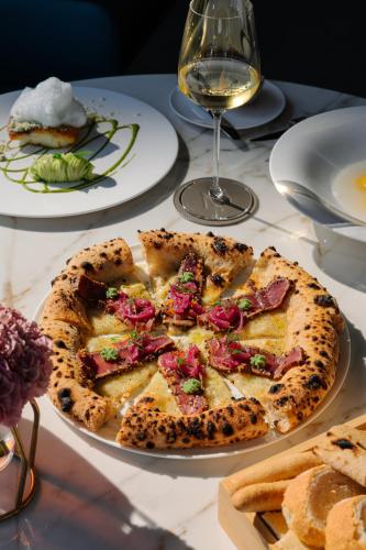 a pizza on a table with a glass of wine at Grand Hotel Victoria concept & spa, by R Collection Hotels in Menaggio