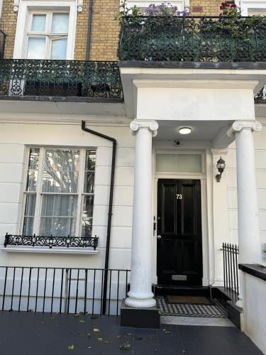 a white house with two columns and a black door at Hyde Park Suites in London