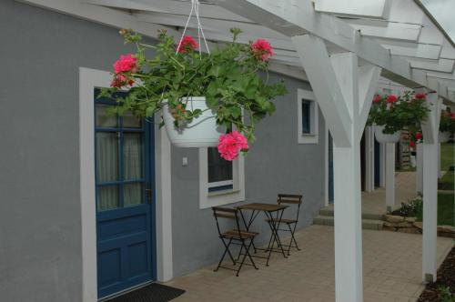 a porch with a blue door and a table with pink flowers at Szerencsepatkó Vendégház in Cserszegtomaj
