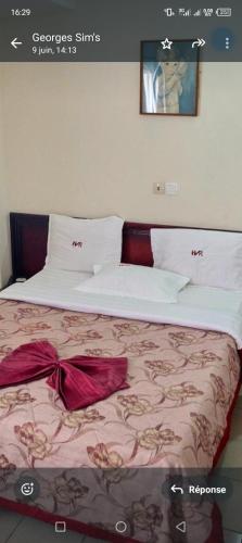 a bedroom with a large bed with red sheets and pillows at Hôtel vallée des rois in Douala