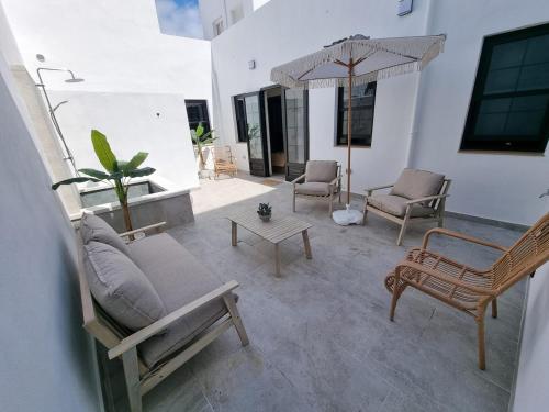 un patio con divano, sedie e ombrellone di Retiro Costa de Lava Garachico a Garachico