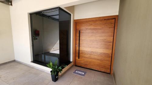 a wooden door in a room with a plant next to it at Casa Espetacular, 3 suites, luxo! in Maringá
