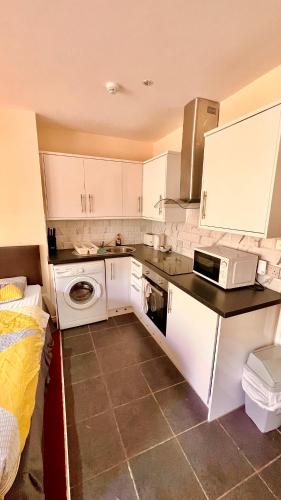 a small kitchen with white cabinets and a microwave at Castle Lodge Guest House 86-88 Sheil Rd L6 3AF in Liverpool
