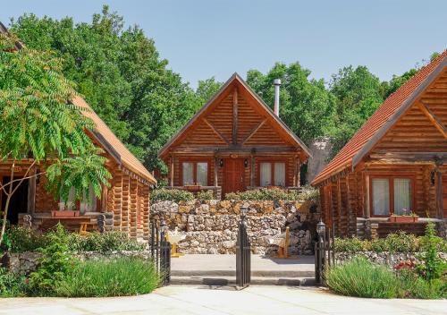 a couple of wooden houses with a stone wall at Wood Hills Hotel & Resort in Mayrūbā