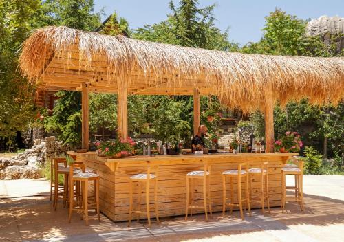 a wooden bar with a straw umbrella and chairs at Wood Hills Hotel & Resort in Mayrūbā