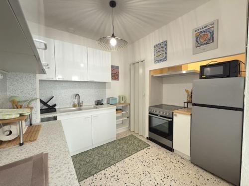  La cuisine est équipée de placards blancs et d'un réfrigérateur. dans l'établissement Valras-Loc Appartement cosy a 300m de la plage, à Valras-Plage