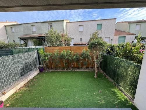 une arrière-cour avec une clôture et un petit jardin dans l'établissement Valras Charme & Mer Proche, à Valras-Plage