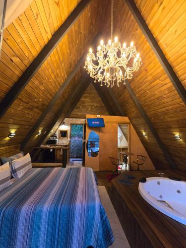 a large bedroom with a large bed and a chandelier at Chalés Capivari Cristal in Campos do Jordão