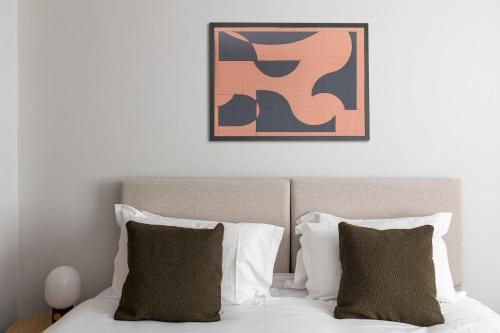 a bed with two pillows and a painting above it at Cove Minshull Street in Manchester