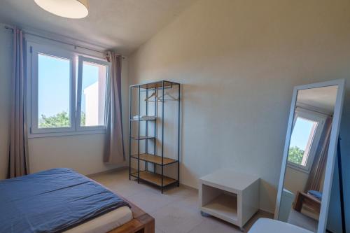 a bedroom with a bed and a shelf and two windows at Il Sughereto In Vigna in Aglientu