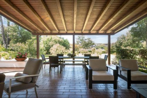 a patio with a table and chairs and a wooden ceiling at Villa Capinera, intera casa con parco privato in Punta Ala