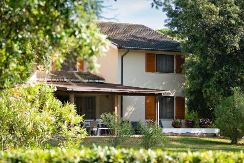 a house with a porch and chairs in the yard at Villa Capinera, intera casa con parco privato in Punta Ala