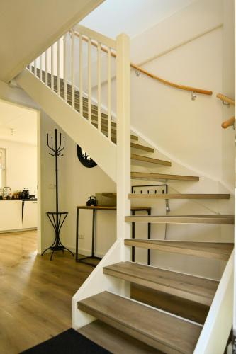a white staircase in a living room with wood floors at Villa Maroma Regal luxueus verblijf voor zakelijk en privé met gratis 4 E-bikes in Kamperland