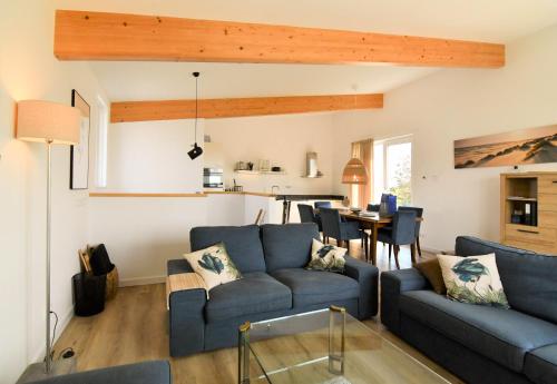a living room with a blue couch and a table at Villa Maroma Mistral Veerse Meer gratis 4 E-bikes gratis laden EV trampoline in Kamperland