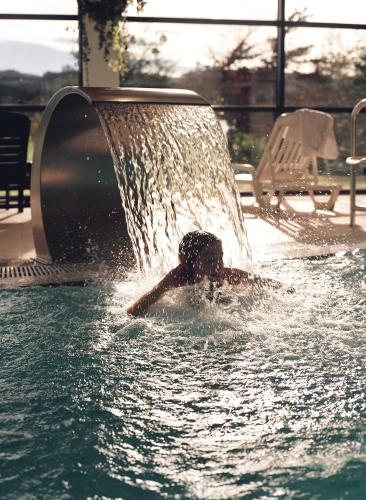 a person is in the water under a fountain at Oca Palacio De La Llorea Hotel & Spa in Deva