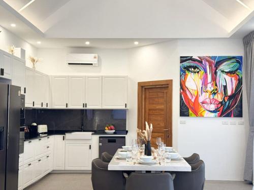 a kitchen with a table and a painting of a woman at Villa Lulu Chic 2BR Seaview Retreat Private Pool in Ban Lamai