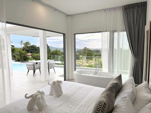 two stuffed animals sitting on a bed in a bedroom with a tub at Villa Lulu Chic 2BR Seaview Retreat Private Pool in Ban Lamai