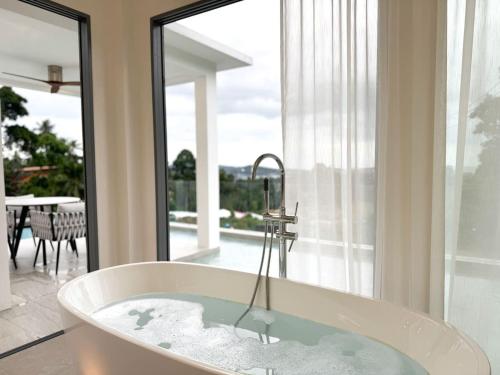 a bath tub in a room with a large window at Villa Lulu Chic 2BR Seaview Retreat Private Pool in Ban Lamai