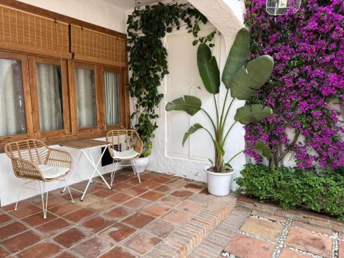 a patio with a table and chairs and purple flowers at El Cortijillo 503 in Almuñécar