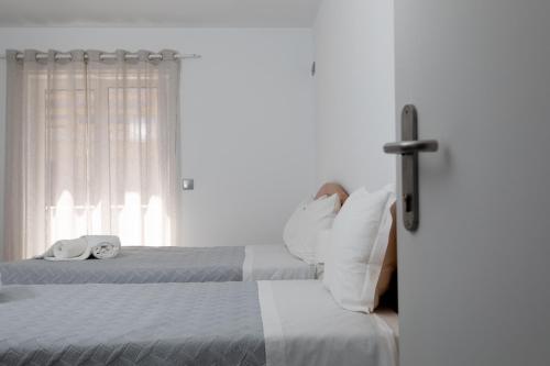 a bedroom with two beds and a cross on the wall at Residencia Salva-Vidas in Nazaré