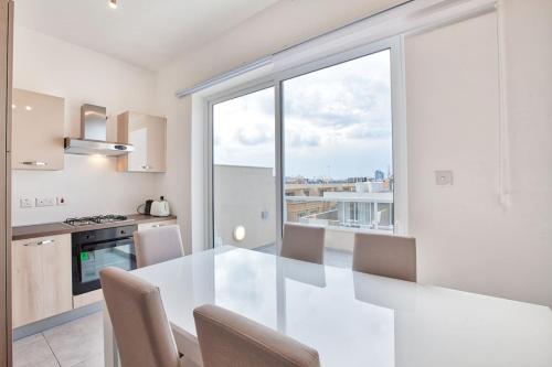 una cocina con una mesa blanca y una ventana grande en Mercury Residence No15 Penthouse Terrace by Haven & Keys Malta, en Sliema