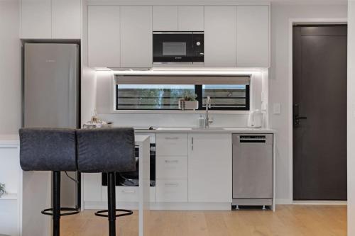 a white kitchen with a sink and a microwave at Modern Townhouse close to Airport and Hospital in Auckland