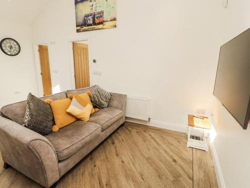 a living room with a couch and a clock on the wall at Lakes View Apartment 2 in Carnforth