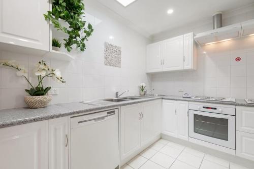 a white kitchen with white cabinets and a sink at 9-3 Glenelg Place Connolly A9 Elegant 3 bed apt in the heart of Connolly in Perth