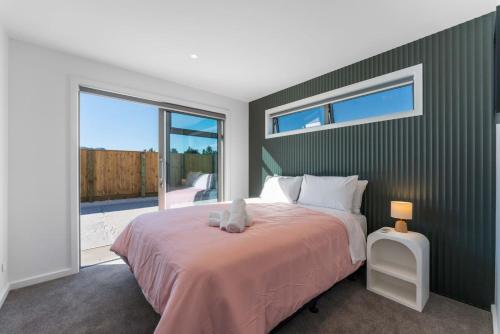 タウポにあるLuxe Family Haven in Wharewakaの大きなベッドと大きな窓のある寝室