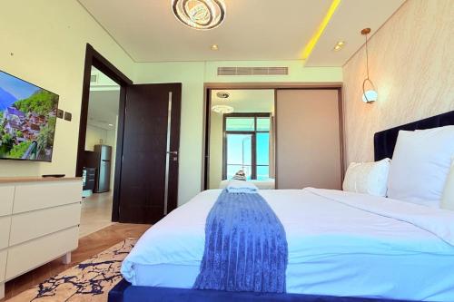a bedroom with a large bed with a blue dresser at Blue Seaview 75 inch Smart TV 1Br in Manama