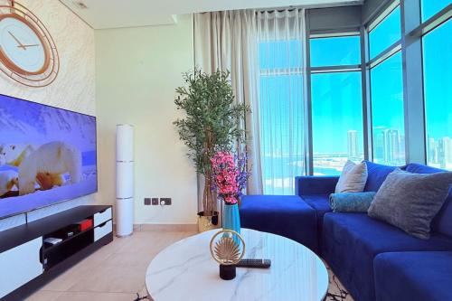 a living room with a blue couch and a table at Blue Seaview 75 inch Smart TV 1Br in Manama