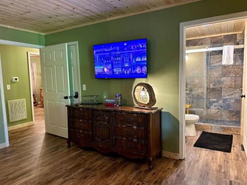 ein Badezimmer mit einer Holzkommode und einem Fernseher an der Wand in der Unterkunft Laurelwood Luxury Cabin Hot Tub in Cosby