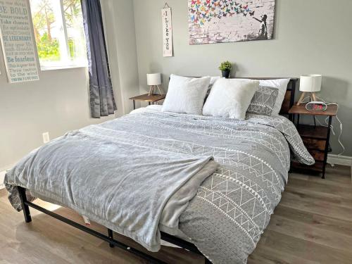 a bedroom with a bed with a gray comforter and pillows at Cozy Retreat with Netflix and Work Desk in Fort Erie