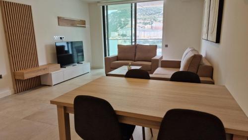a living room with a table and chairs and a television at Pool, views and Relaxation in Gibraltar