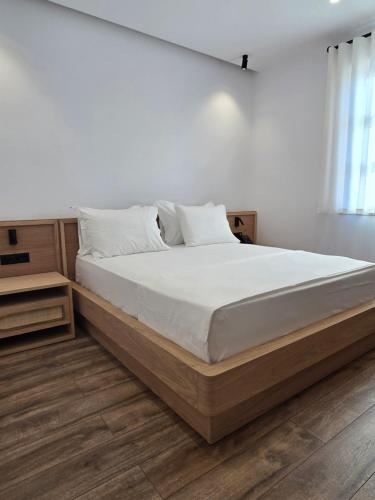 a bedroom with a large bed with white sheets at Palorto Inn in Gjirokastër