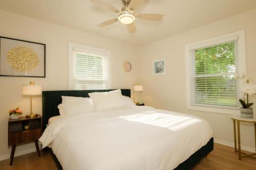 een slaapkamer met een groot wit bed en een plafondventilator bij Heights Haven on Paris - 2BD Stay in Peoria Heights
