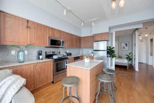 a kitchen with wooden cabinets and a kitchen island with stools at Ent District 3 Bedroom 2Bath Parking CN Tower in Toronto