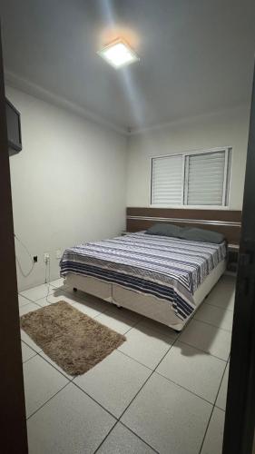 a bedroom with a bed in the middle of a room at Apto Aconchegante Araguari MG in Araguari