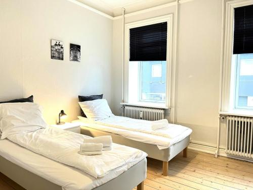 two beds in a room with two windows at Spacious Apartment for 6 in Frederikshavn