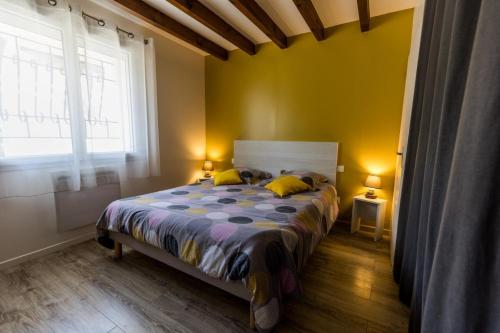 a bedroom with a bed with yellow walls and a window at Gite salis in Toulouzette