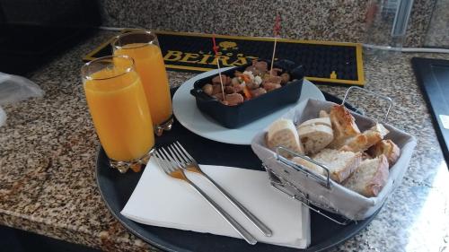 a tray with a plate of bread and two glasses of orange juice at Golden Mirror in Lamego