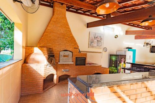 a kitchen with a brick wall with a fireplace at Chácara em São Pedro com piscina e churrasqueira in São Pedro