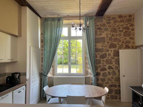 une cuisine avec une table devant une fenêtre dans l'établissement Gîte du Sacré-Coeur - Mauléon- proche Puy du fou, à Saint-Aubin-de-Baubigné