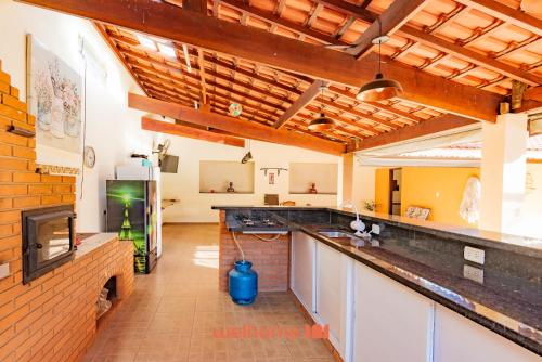 a large kitchen with a counter and a fireplace at Chácara em São Pedro com piscina e churrasqueira in São Pedro