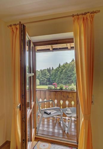 una porta che si apre su un balcone con tavolo e sedie di Wohnung Falkenstein a Spiegelau